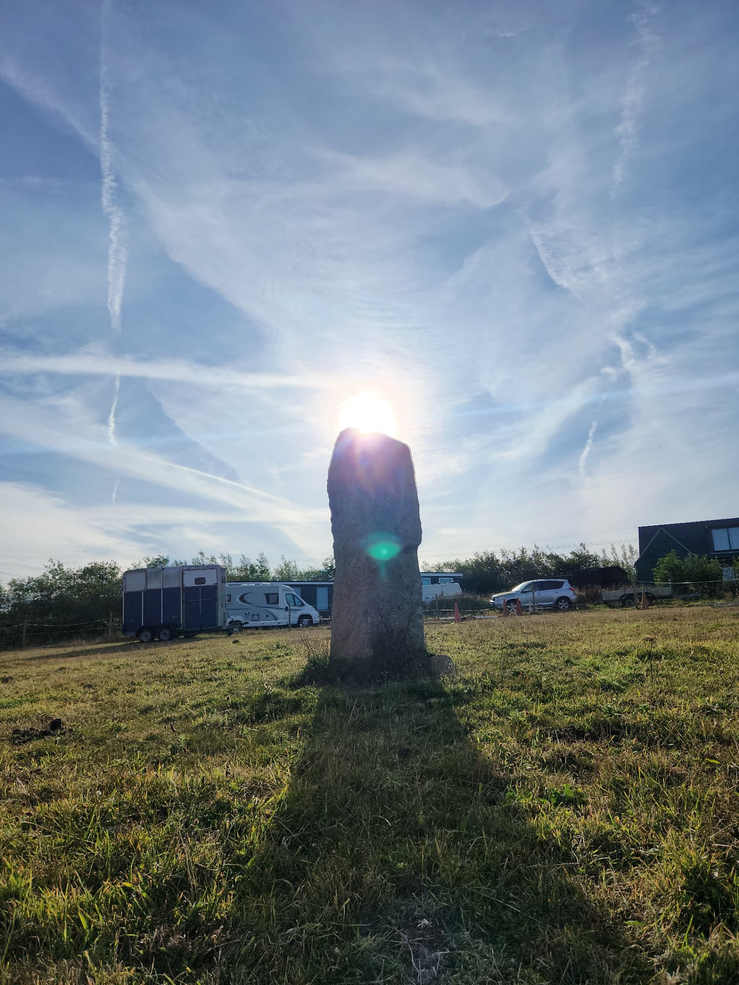A single granite standing stone raised in a Cornish field at sunset, part of the star map alignment